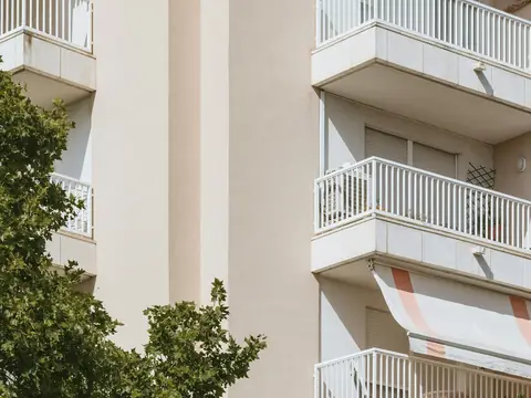 Balkonlu, açık renkli apartman cephesi ve ağaç